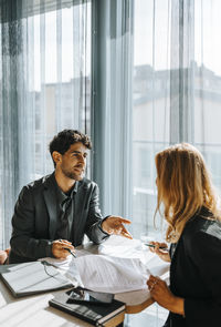 Male client talking with businesswoman while doing paperwork at office
