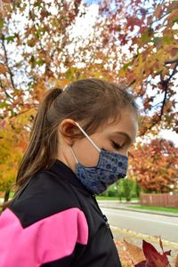 Portrait of girl looking away while sitting on tree