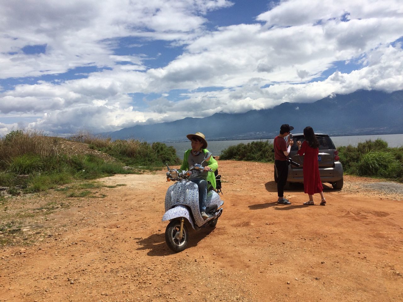 REAR VIEW OF COUPLE SITTING ON ROAD AGAINST MOUNTAIN