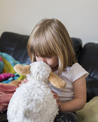 Girl playing with stuffed toy on bed