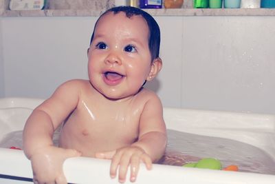 Thoughtful cute naked baby girl in bathtub