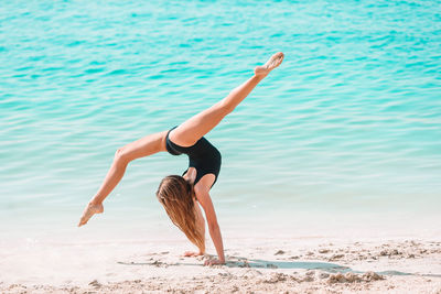 Full length of woman with arms raised on beach