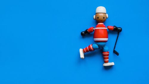Close-up of wooden toy figurine over blue background