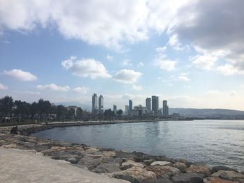 Sea by buildings against sky