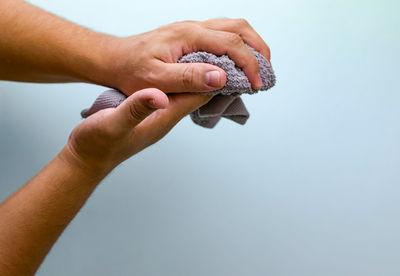 Cropped hand of person holding ring against blue background