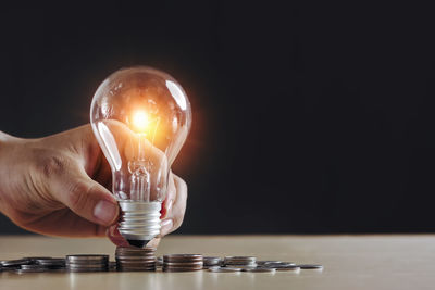 Close-up of illuminated light bulb on table against black background