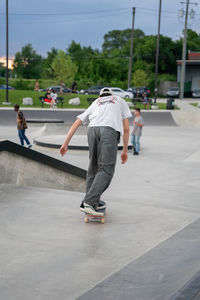 Rear view of man skateboarding on road