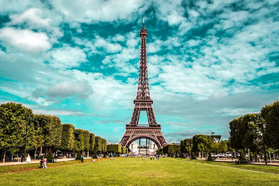 Communications tower in city against cloudy sky