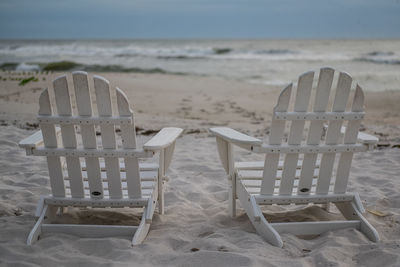 Empty chairs on beach against sea