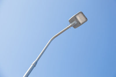 Low angle view of telephone pole against clear blue sky