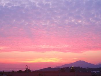 Silhouette trees against dramatic sky during sunset