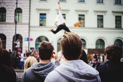 Spectators looking at man performing stunt on street