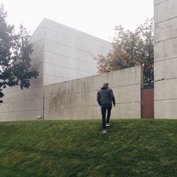 Man walking on field against building