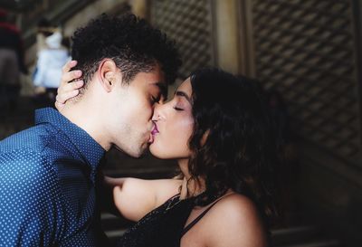 Close-up of couple kissing while standing against wall