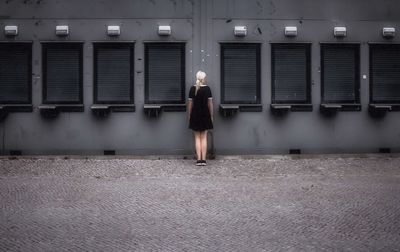 Rear view of woman walking on illuminated wall