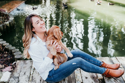 Dog with woman by pond at park