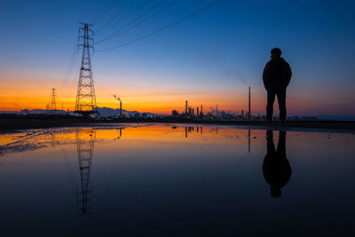 Silhouette woman standing on beach against sky during sunset