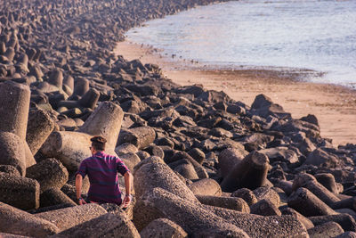 Rear view of woman sitting on rock at beach