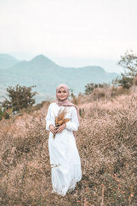 Portrait of young woman standing on field