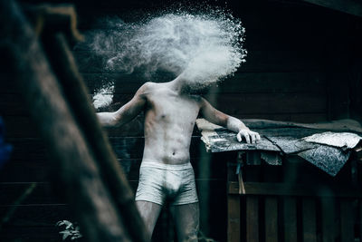 Hopeless shirtless man standing by powder in abandoned house