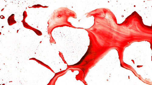 Close-up of red splashing water against white background