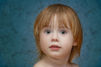 Close-up portrait of cute boy against wall