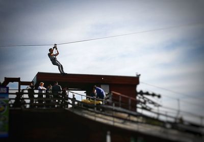 Low angle view of people on rope against sky