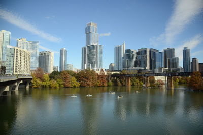 Modern buildings by river against sky in city