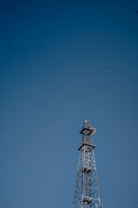 Low angle view of communications tower against clear blue sky