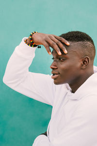 Portrait of young man with arms raised standing against white background