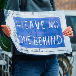 Midsection of man holding text on blue sign