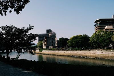 River by buildings against clear sky