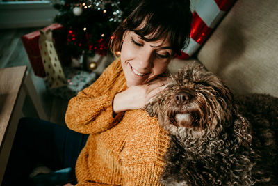 Smiling woman sitting with dog at sofa