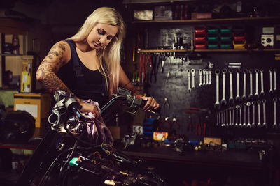 Young woman cleaning motorcycle at workshop