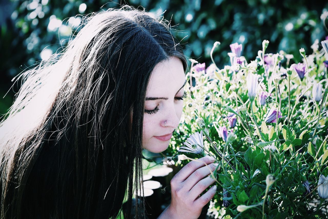 one person, young women, leisure activity, real people, headshot, plant, long hair, lifestyles, young adult, portrait, hairstyle, flower, hair, flowering plant, focus on foreground, looking, women, beauty, day, beautiful woman, contemplation, outdoors, teenager