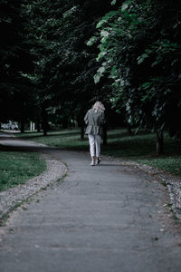 Rear view of woman walking on footpath at park