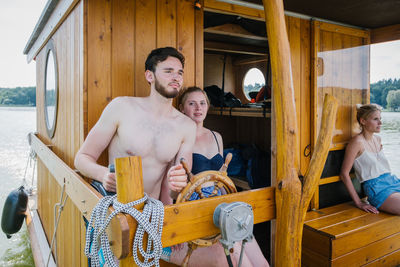 Shirtless man with woman sailing boat in lake