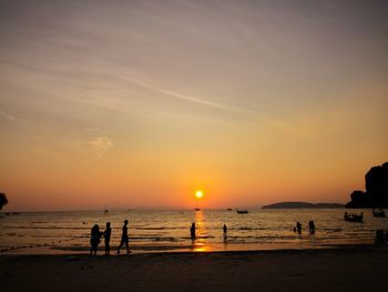 Silhouette people at beach against sky during sunset