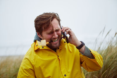 Close-up of man using mobile phone against sky