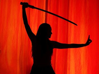 Silhouette woman standing against orange wall