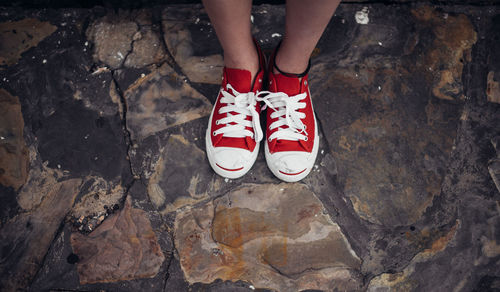 Low section of woman wearing red shoes while standing on footpath