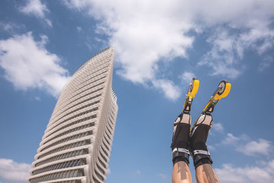 Low section of man with inline skates against blue sky