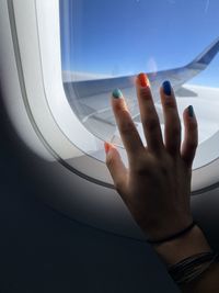 Close-up woman hand touching airplane window