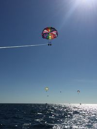 People paragliding over sea against clear sky