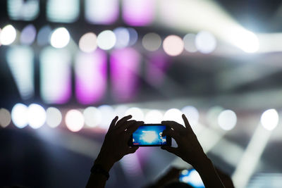 Close-up of hand holding camera phone at night