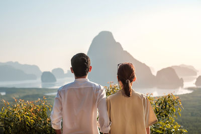 Rear view of people looking at mountains against sky