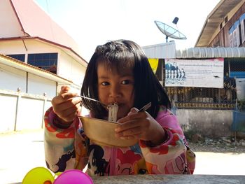 Portrait of cute girl eating noodles at outdoors