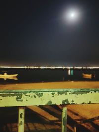 Close-up of illuminated railing against sea at night