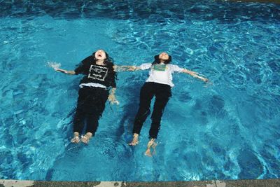 Low section of woman relaxing in swimming pool