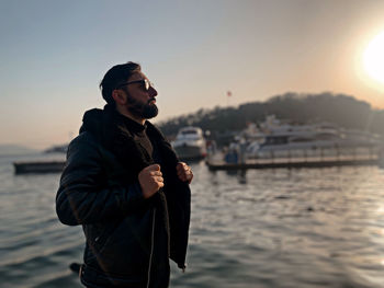 Side view of young man looking at sea against sky